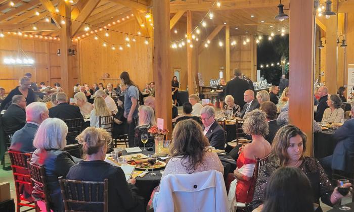 Guests at the Under the Moon Gala sitting at tables for 8 in the decorated Tringali Barn