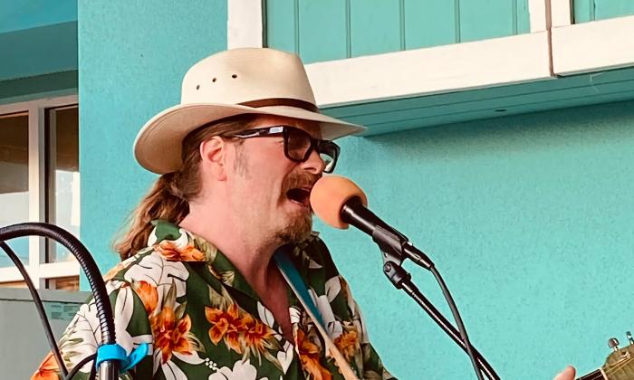 Michael P. Owen performing outside a bright teal building