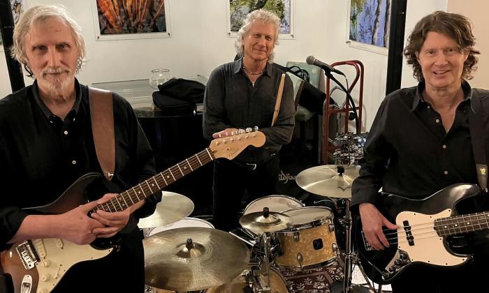 The trio, Sidewalk 65, standing together with their instruments