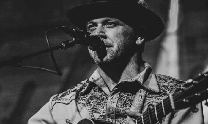 Gent Treadly strums his guitar on stage for fans.