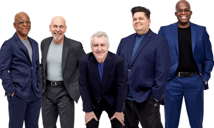 Bandmates from Spyro Gyra smile and pose in front of a white backdrop.