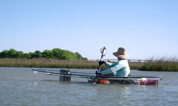 A kayaker in a transparent kayak with a view of Vilano Bridge