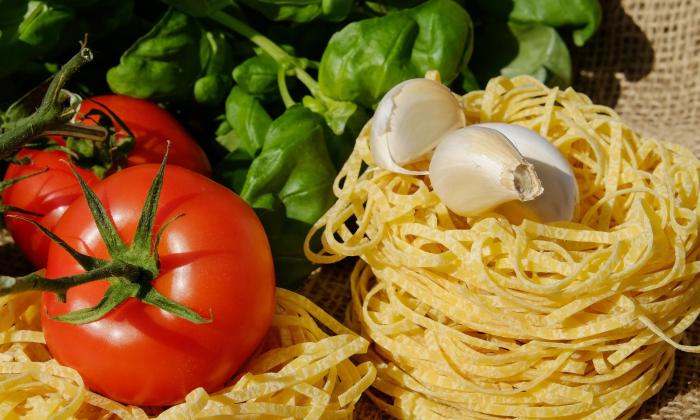 A red, green and white display of fresh foods, tomato, basil, garlic, and pasta