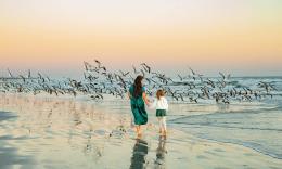 A mother and daughter walking on the beach