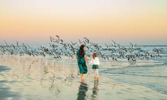 A mother and daughter walking on the beach