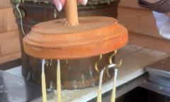 Candles hung by their wicks being dipped in beeswax