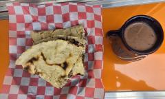 A tlayuda with a hot beverage to the side