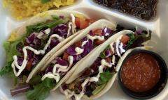 Tacos with a side of salsa in a to-go box