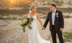 A bride and groom walking on the beach