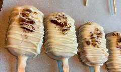 A row of cake pops topped with pecans