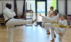 An instructor teaching kids how to kick