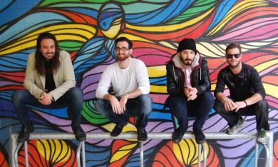 The band poses with a colorful background.