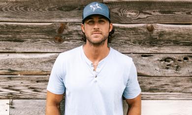 Riley Green poses in front of a wood backdrop