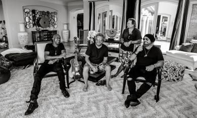 Sammy Hagar & The Circle pose in a spacious room with dark-colored drapes 