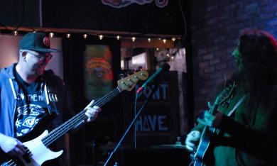 Two members of the band Zalongo playing their bass and guitar onstage at Planet Sarbez.