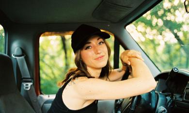 Lauren Hungate at the wheel of her truck, parked by a grove of trees