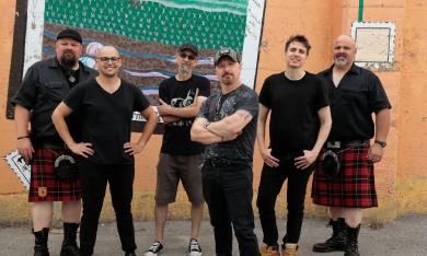 Members of the Celtic band, the Mudmen, stand outside against a painted wall