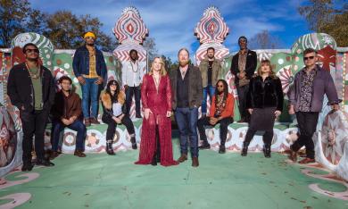 The 12-member Tedeschi Trucks Band arranged within a brightly painted outdoor space