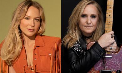 Jewel poses in a orange jacket, while Melissa Etheridge poses in a black jacket while holding her guitar. 