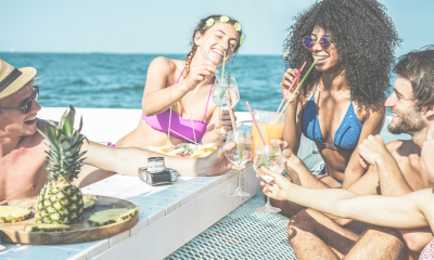 Two couples on a catamaran, enjoying drinks and snacks in the sun
