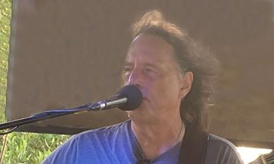 Singer songwriter David Watt Besley, with microphone, singing onstage, outside