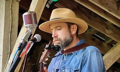 Musician DAve Schottland playing guitar onstage, outside.