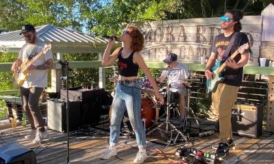 The four member group, The Band Madam, performing on an outside stage on a sunny day