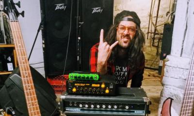 A musician at his mixer, with hat backwards, tongue out, and showing the sign of the horns