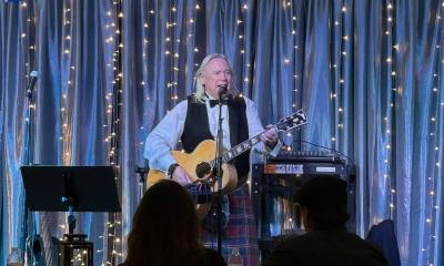 Bill Mullen on stage with his guitar, in front of a live audience