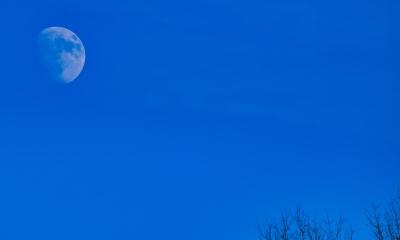 A nearly full moon in a dark blue sky