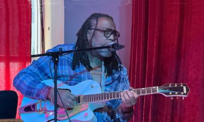 Guitarist Erick Carter, in blue, performing in front of a red curtain