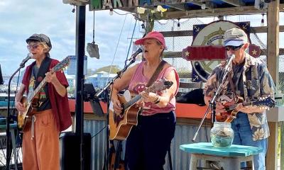 The band Honey Knots at a marina perfoming with guitars and mandolin.