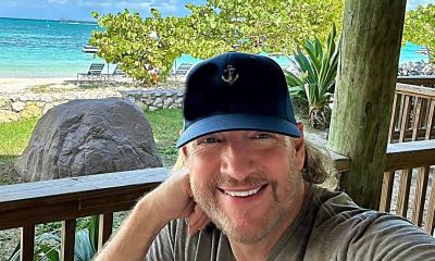 Smiling Anthony Smith in black cap, with view of tropical island in the background