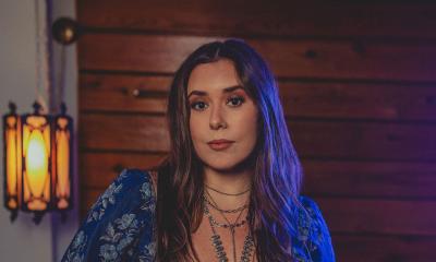 Songwriter Jenna LaMaster headshot with warm wooden wall behind.