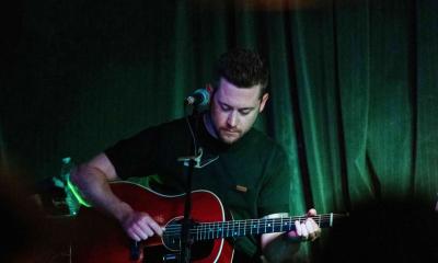 Songwriter Sam Banks with guitar, on stage