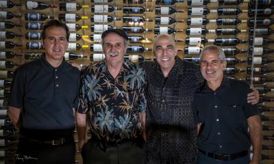 House Cats band in front of a wall of sine bottles. Photo courtesy of Terry Bottom photography