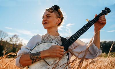 Sparrow Smith with her banjo on a sunny day in a field