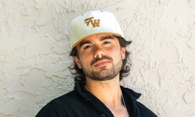 Composer Emmett Stevens, Jr standing in front of white wall, in a ball cap