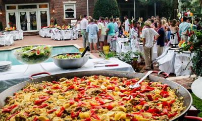 A large dish of paella at an outdoor party.
