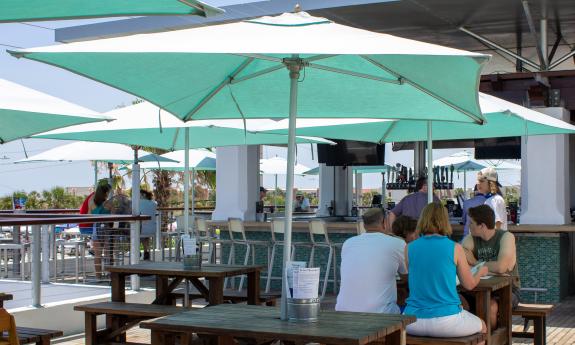 Green umbrellas shade the tables on the deck of the Salt Life Food Shack. 