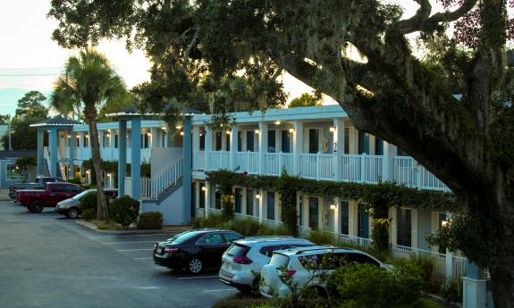 A view at night of a two-storied hotel/motel with upper deck and parking.