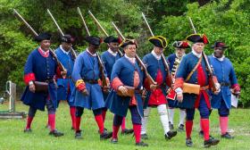 Historic reenactors marching on the Fort Mose grounds
