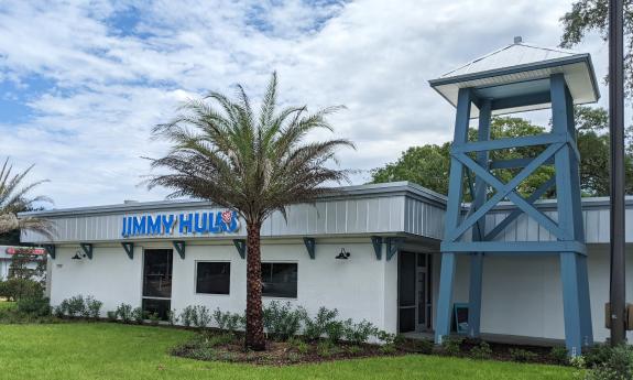 The exterior of Jimmy Hula's restaurant with grey, flat-topped building with tower