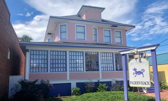 A art and gift store in an old pink house with a multi-paned windowed porch. 