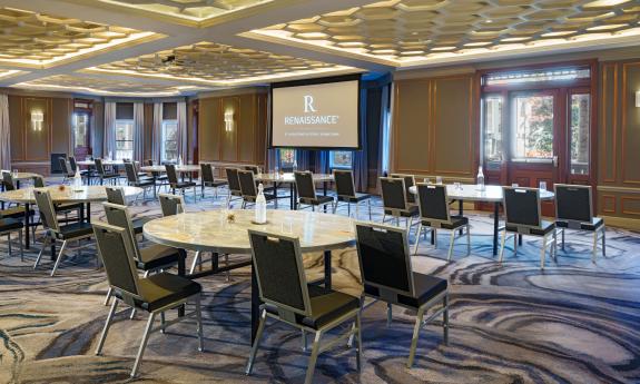 A hotel conference room set up with round tables facing a screen