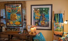 Brightly colored framed art, fabric art, and lamps against a yellow wall