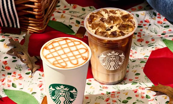 Hot and cold Starbucks coffee on a table decorated for the fall season. 