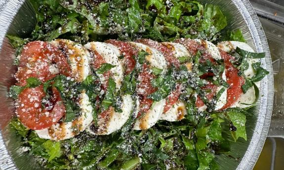 A Caprese salad on a bed of seasoned greens