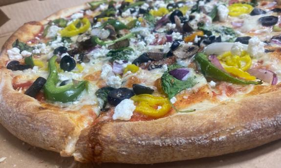 A whole pizza, loaded with veggies, ready to be boxed and delivered