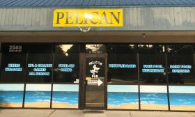 The door to Pelican Pub, with a sun-hit yellow sign and a list of amenities
